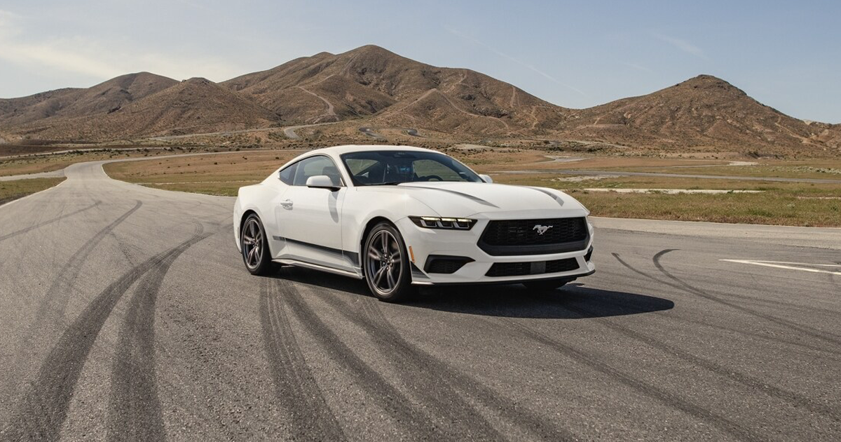 A Ford Mustang parked at an angle on a road by mountains